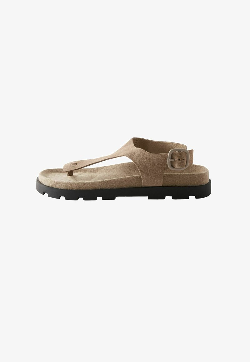 Tan suede sandal with toe post and ankle strap, featuring a black rubber sole and a metal buckle for adjustable fit.