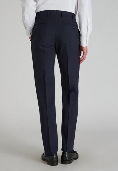 Marineblaue, maßgeschneiderte Hose mit glatter Textur, zwei Gesäßtaschen und Kontrastnähten, kombiniert mit schwarzen Schnürschuhen.