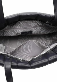 Interiér námořnické kožené kabelky s šedým vzorovaným podšíváním; obsahuje kapsu na zip a dva vnitřní prostory pro organizaci.