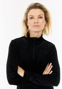 Zwarte zip-up pullover met hoge kraag, textiel met subtiele verhoogde patronen, lange mouwen en een aansluitende pasvorm.