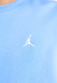 Világoskék pamut póló, amelyen egy kis fehér Jumpman logó található a bal mellrészen. Sima textúrájú, kerek nyakú.