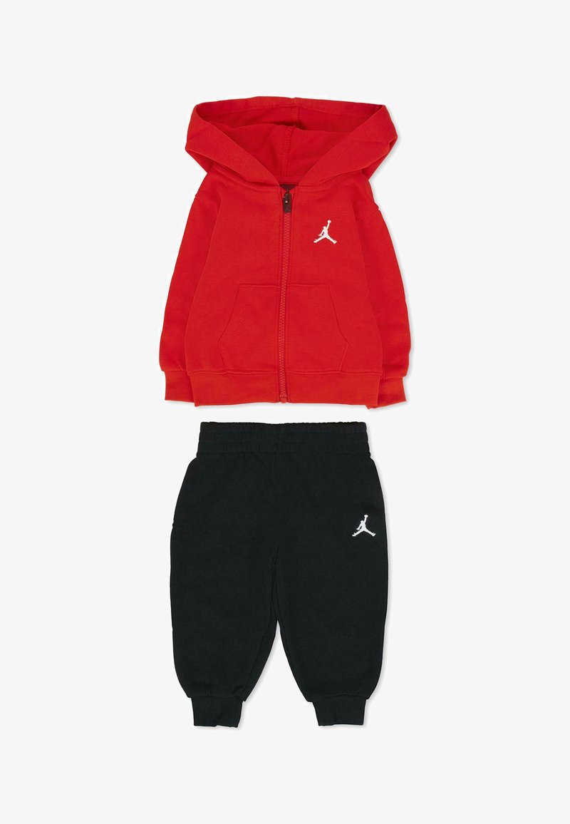 Rode hoodie met rits en kangoeroezakken, voorzien van een wit Jordan-logo. Zwarte sweatpants met elastische manchetten en bijpassend wit logo.