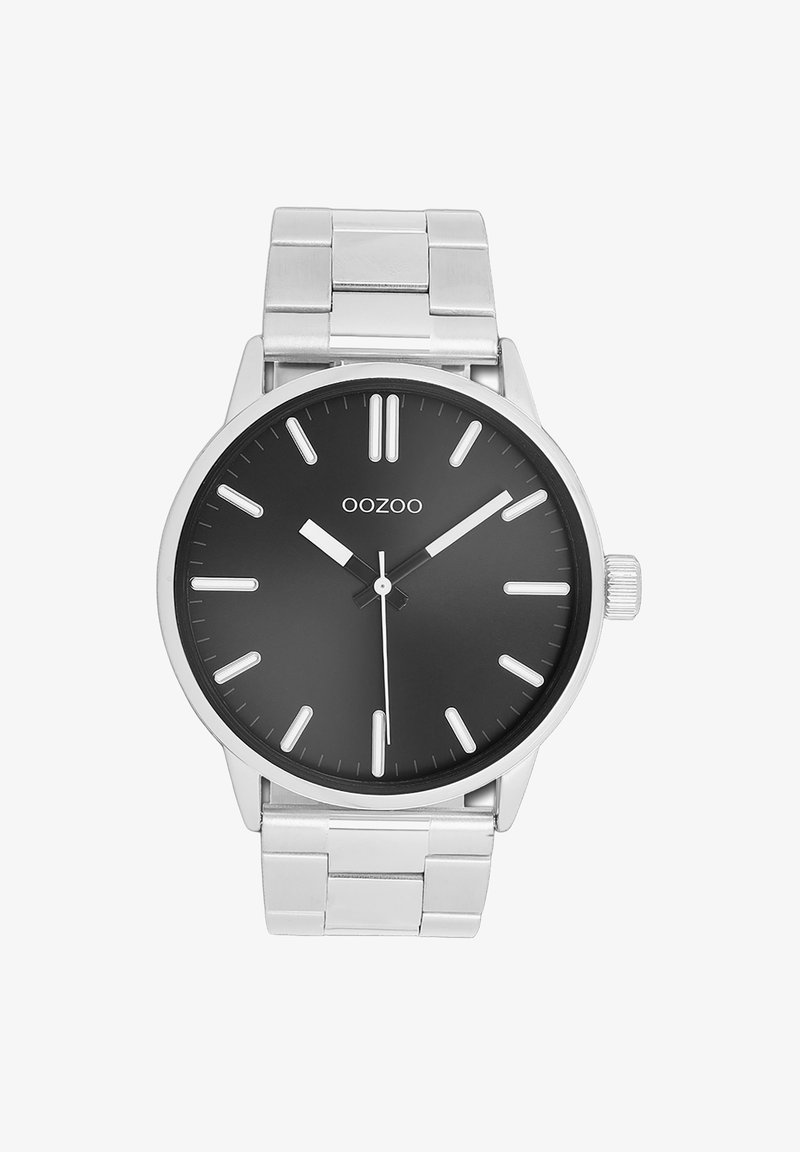 Montre-bracelet en métal argenté avec un cadran rond noir, des marqueurs des heures blancs et des aiguilles argentées. Elle possède un bracelet en acier inoxydable et une couronne proéminente.