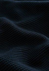Donkerblauwe gestructureerde stof met een golvend patroon, dat een zachte, geribbelde oppervlakte laat zien die diepte en visuele interesse creëert.