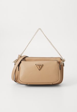 Beige textured leather shoulder bag with gold chain strap, front zip pocket, and triangular Guess logo plaque.