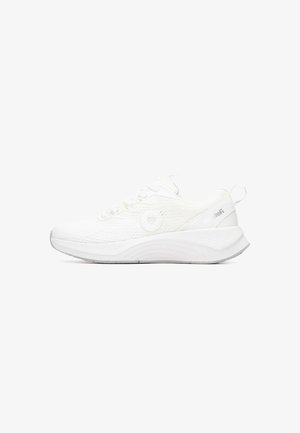 Zapatilla deportiva blanca con parte superior de malla texturizada, suela flexible y talón redondeado. Presenta cordones y un detalle circular en el lateral.