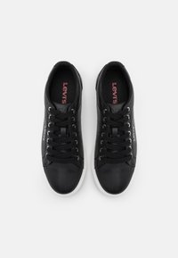 Svarta lädersneakers med en slät yta, rund tå, vit gummisula och svarta snören. Har "Levi's"-logotypen i röd färg på innersulan.