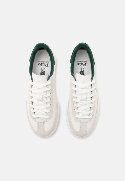 Paire de baskets blanches Polo Ralph Lauren avec doublure intérieure verte et lacets blancs vues d’en haut sur un fond uni.