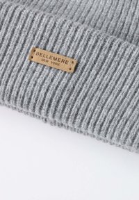 Berretto a maglia grigia con righe, dotato di un'etichetta in pelle che riporta la scritta "BELLEMERE NEW YORK." Tessuto testurizzato, finitura morbida e design aderente.