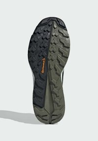 Suela de zapato de goma con profundas estrías en negro y verde oliva, que presenta el logo "Continental" en naranja, diseñada para ofrecer tracción.