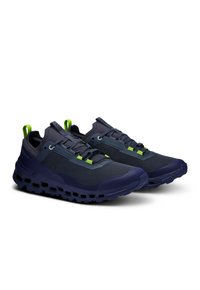 Marineblau laufschuhe mit einer strukturierten Oberseite, grünen Akzenten, einer gepolsterten Sohle mit Ausschnitten und verstellbaren Schnürsenkeln. Leichtes Design.