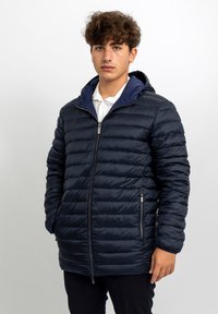 Giacca imbottita blu navy con chiusura frontale con zip e tasche laterali. Presenta un cappuccio e una texture trapuntata, adatta per il freddo.