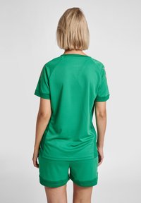 Grön sporttröja med korta ärmar, tillverkad av andningsbart tyg, med mönstrad struktur och kontrasterande detaljer på axlarna.