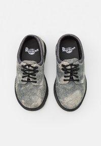 Szare skórzane buty o teksturowanej powierzchni z czarnymi sznurówkami, zaokrąglonym kształcie i gumowej podeszwie; na wkładkach znajduje się logo Dr. Martens.