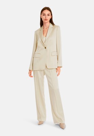 Light beige tailored suit featuring a single-button blazer with two front pockets and wide-leg trousers, made from a smooth fabric.