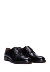 Chaussures en cuir noir avec une finition texturée, dotées d'un bout arrondi, d'un design classique à lacets et d'un talon bas et plat.