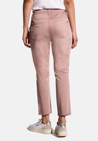 Vaaleanpunaiset, istuvat housut, joissa on viisi taskua ja hienovaraiset ompeluyksityiskohdat. Yhdistetty valkoisiin ja hopeisiin tennareihin, suorat lahkeet.