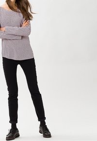 Světle fialový pletený svetr s designem na jedno rameno, doplněný černými slim-fit kalhotami a černými šněrovacími botami.