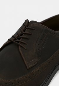 Smeđe kožne cipele za odijela s glatkom površinom, s okruglim prstom, brogue detaljima i smešnim vezanjem.