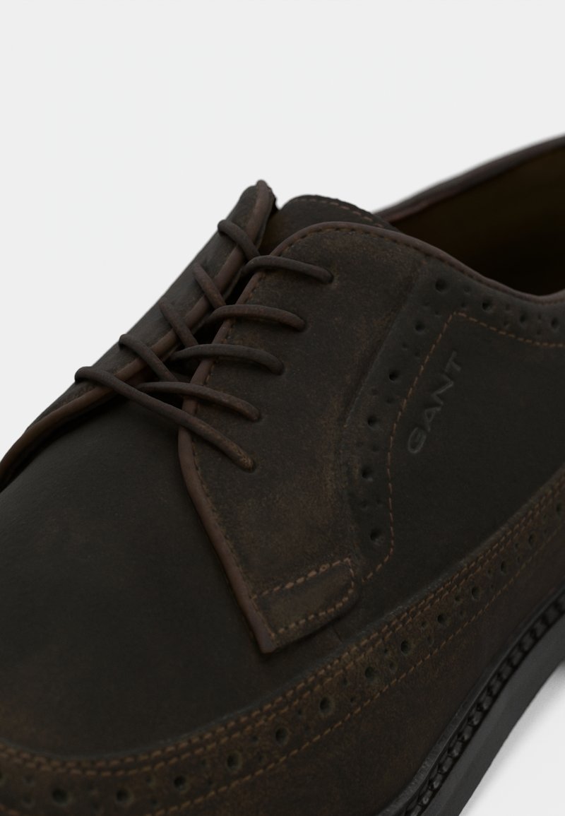 Chaussure habillée en cuir brun avec une finition lisse, dotée d'un bout arrondi, de détails en brogue et d'un laçage brun.