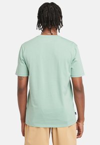 Mátově zelené tričko s krátkým rukávem a kulatým výstřihem. Hladká bavlněná tkanina, volný střih a detail na bočním štítku.