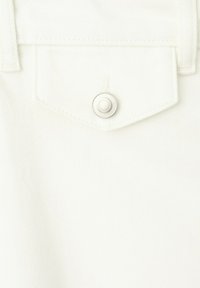 Tissu en denim blanc avec un rabat de poche pointu maintenu par un seul bouton-pression argenté.