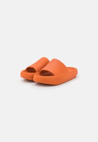 Orange slide sandaler med en texturerad yta, öppen tådesign och tjock plattformssula. Tillverkade av hållbart, flexibelt material.