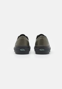 Sapatilhas de lona verdes com bico arredondado, sola de borracha preta e logo "Vans Off The Wall" no calcanhar. Textura suave, sem padrões.