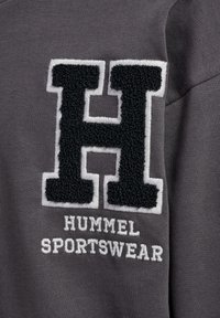 Szara bluza z teksturowanym czarnym logo "H" obramowanym na biało oraz haftowanym białym napisem "HUMMEL SPORTSWEAR".