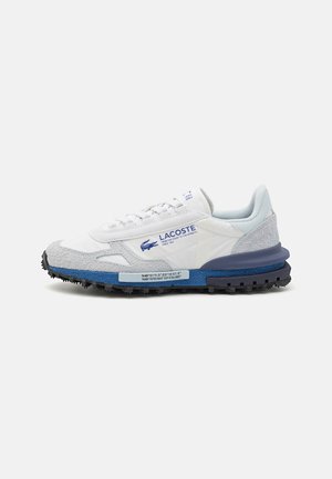 Zapatillas Lacoste con parte superior de cuero blanco y detalles en gamuza gris, una entresuela texturizada azul y suela de goma para mayor tracción.