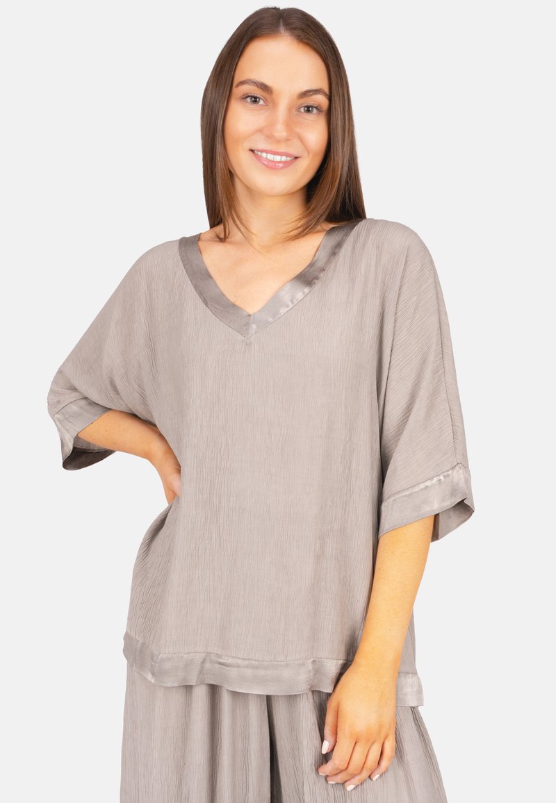 Lockere graue Bluse mit V-Ausschnitt, kurzen Ärmeln und Satinakzenten. Die Textur ist leicht zerknittert, was visuelles Interesse verleiht.
