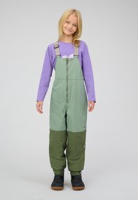 Groen en grijs tweekleurig waterdicht overalls met verstelbare bandjes, ritssluiting aan de voorkant en elastische manchetten, gecombineerd met zwarte laarzen.