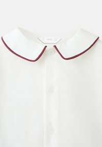 Bijela dječja majica s okruglom ovratniku detaljno u tamnocrvenoj boji i tri gumba sprijeda, oznaka veličine vidljiva unutar ovratnika.