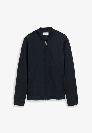 Jachetă bleumarin cu fermoar, mâneci lungi, guler în picioare și două buzunare laterale, prezentată pe un fundal alb.