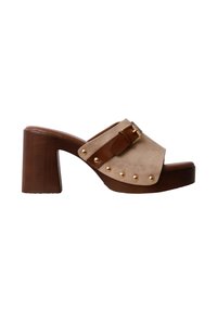Mule en daim beige avec talon bloc en bois marron, clous dorés le long du bord de la semelle, et bride en cuir marron avec boucle dorée sur le dessus.