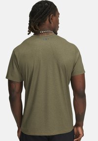 Camiseta atlética verde hecha de tela texturizada. Cuenta con mangas cortas, cuello redondo y sutiles perforaciones en la parte posterior.