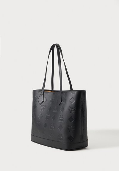 Grand sac cabas en cuir noir avec logo MCM embossé et motifs en forme de diamant, doté de deux longues bandoulières et d'une base rectangulaire.