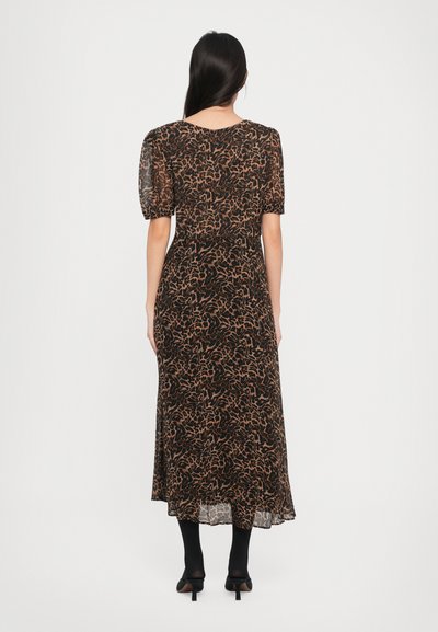 Svart kjole med korte pufferm, med et brunt abstrakt mønster. Flytende design som når midt på leggen, laget av transparent stoff.