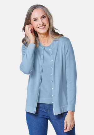 Helles blaues Strickjäckchen und passendes Oberteil, beide mit weicher Textur. Das Strickjäckchen hat einen runden Halsausschnitt, lange Ärmel und eine Knopfleiste.