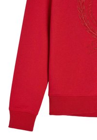 Czerwony sweatshirt z ściągaczami na rękawach i u dołu. Ozdobiony haftowanym motywem laurowym w uzupełniającym kolorze. Miękka struktura, luźny krój.