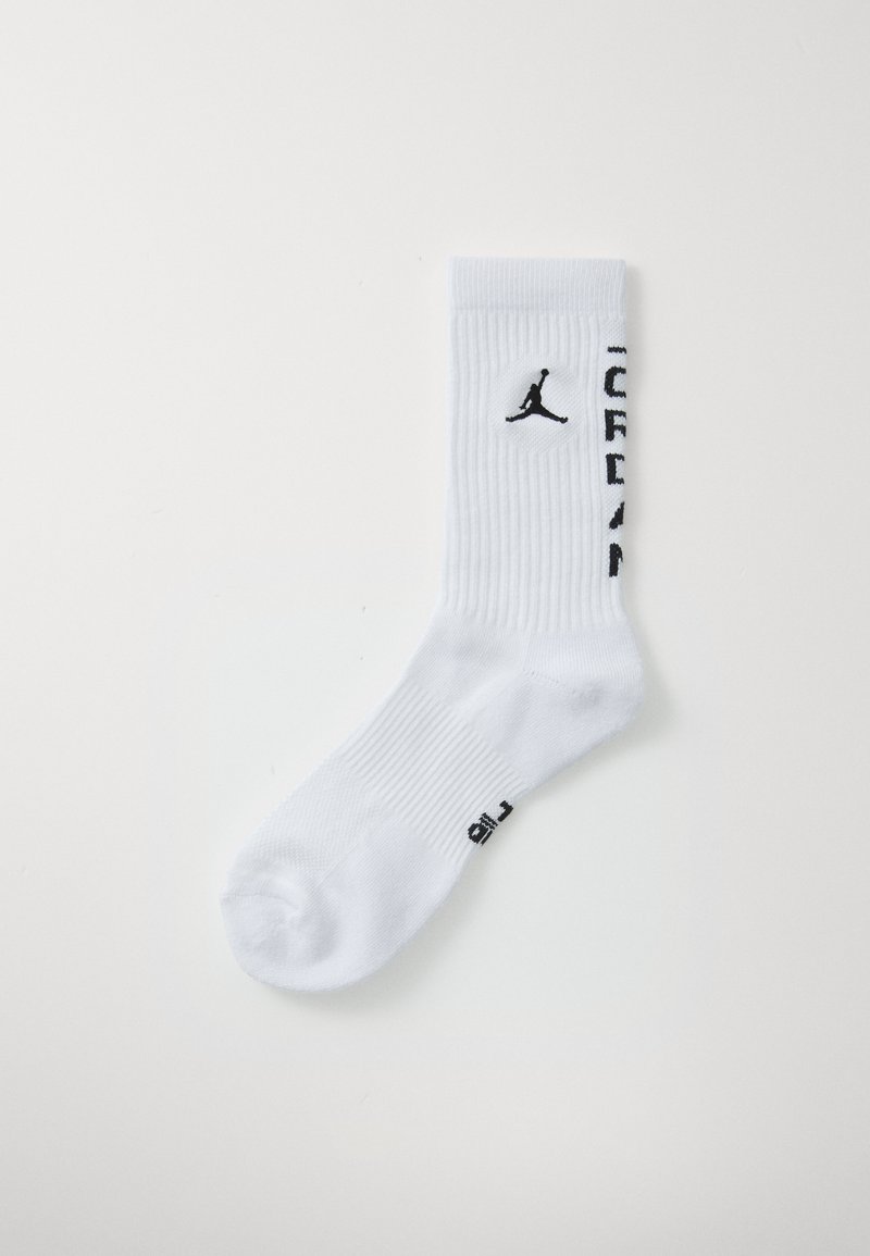 Calcetín de crew blanco con textura acanalada, con el logo negro de Jumpman y el texto "JORDAN" en el lateral, tendido sobre un fondo blanco.