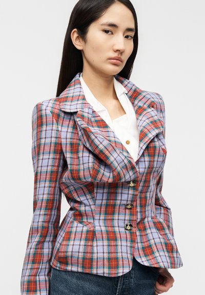 Καρό σακάκι σε μπλε, κόκκινο και λευκό χρώμα· διαθέτει αιχμηλή πέτο, σφιχτή μέση και χρυσά κουμπιά· υφασμάτινη υφή με ελαφριά γυαλάδα.