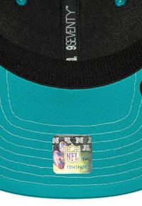 Casquette turquoise avec intérieur noir ; présente des coutures blanches. Comprend une étiquette avec le logo NFL et des détails holographiques sur le dessous.