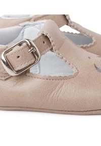 Brązowe skórzane buty z wyciętym wzorem i falbaniastymi krawędziami, z srebrnym zapięciem na klamrze. Miękka teksturowana powierzchnia z delikatnym przeszyciem.