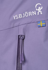 Lila isolerad jacka med ISBJÖRN-logotyp i vitt, en zipficka med lila dragkedja och en blå och gul flaggdetalj.