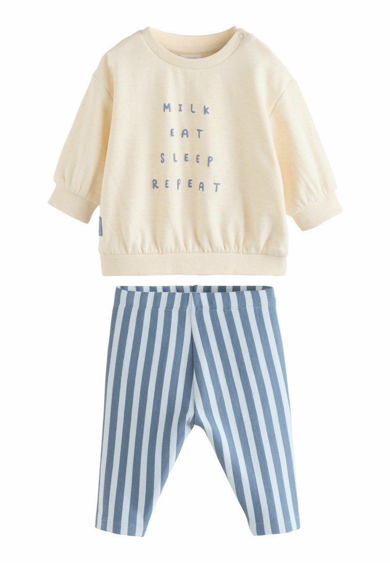 Cremefarbener Sweatshirt mit dem Text „MILK EAT SLEEP REPEAT“, kombiniert mit blauen und weißen gestreiften, weichen Hosen. Beides aus Baumwolle gefertigt.