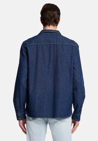 Dunkelblaue Jeanshemd mit langen Ärmeln, Kragen und Knopfdetails an den Manschetten; hat einen geraden Saum und ein minimalistisches Design.