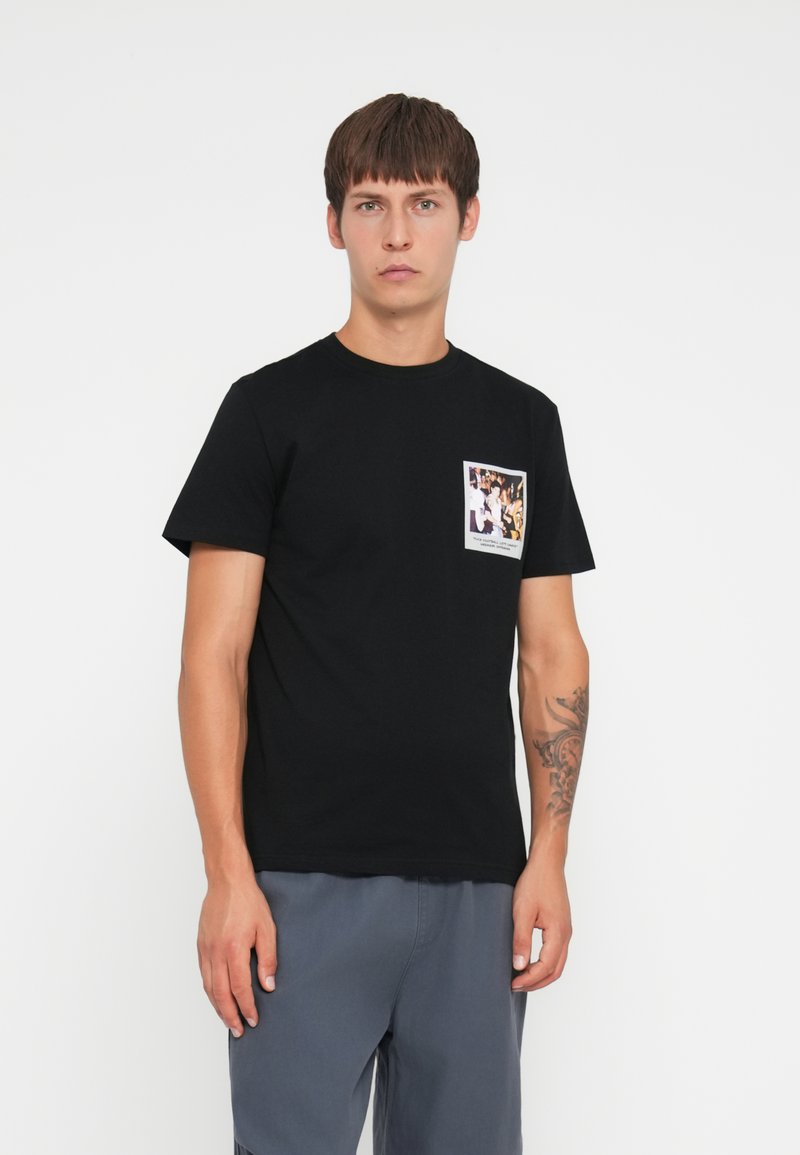 Black cotton t-shirt featuring a front pocket print with a multicolored photo. Classic crew neck and short sleeves, regular fit.