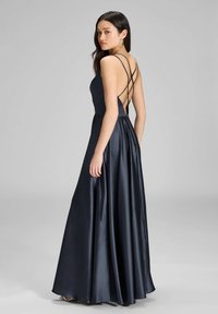 Lungo abito navy caratterizzato da un corpetto aderente con sottili spalline incrociate sul retro e gonna in satin fluente con una texture liscia.