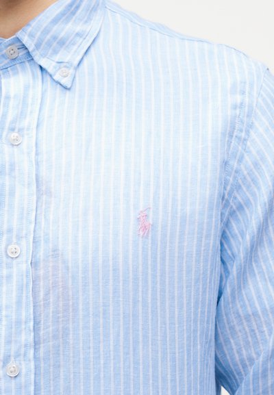Πουκάμισο με κουμπιά σε ανοιχτό γαλάζιο και λευκές ρίγες, με ροζ κεντητό λογότυπο αλόγου και αναβάτη στο στήθος.